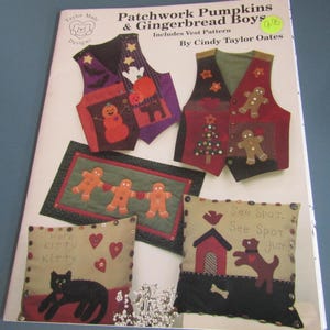 May include: A craft pattern book titled Patchwork Pumpkins & Gingerbread Boys by Cindy Taylor Oates. The cover displays two vests with seasonal appliques, a rectangular wall hanging with gingerbread figures, and two pillows featuring cat and dog designs.