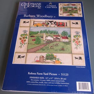 May include: A counted cross-stitch kit featuring a farm scene with a barn, cows, and pumpkins. The kit includes 14-count cotton oatmeal cloth, floss, needle, chart, and instructions. Finished size is 14" x 11". The package is blue with the Candamar Designs logo.
