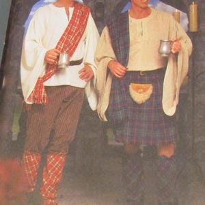 May include: Two people in Scottish Highland attire. One wears a white tunic, brown pants, and a red plaid sash and leg wraps. The other wears a beige tunic, a blue and red plaid kilt, and a black hat. Both hold metal tankards.