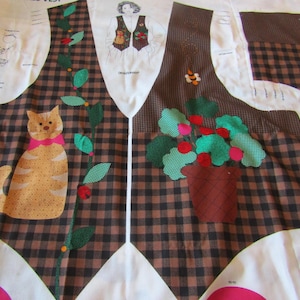 May include: A fabric panel featuring a vest design with a brown and black checkered pattern. The design includes a cartoon cat with a pink bow, a potted plant, and floral accents. The panel also includes a diagram of a person wearing a vest.