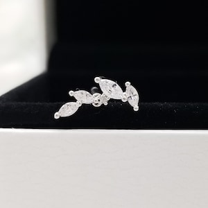 May include: A silver ear cuff with a row of marquise-shaped clear cubic zirconia stones.