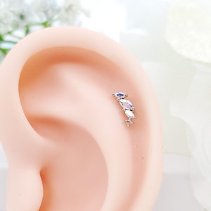 May include: A silver ear piercing with a row of four clear marquise-shaped gemstones.