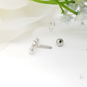May include: A silver body jewellery piece with a clear crystal design. The jewellery is a barbell with a ball on one end and a crystal design on the other end.