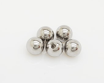 May include: Five silver metal balls, each with a small hole in the center.