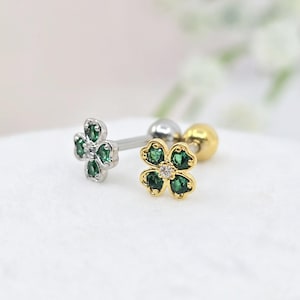 Peut inclure: Deux boucles d'oreilles barre avec un motif de trèfle à quatre feuilles. L'une est argentée avec des pierres vertes, l'autre est dorée avec des pierres vertes. Chaque trèfle possède une petite pierre centrale claire et un fermoir à bille.