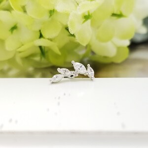 May include: A silver ear cuff with a row of marquise-shaped clear cubic zirconia stones.