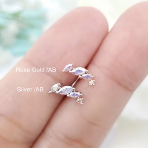 May include: A pair of earrings with a cluster of marquise-shaped crystals in a silver and rose gold finish. The crystals have an iridescent, ab color.
