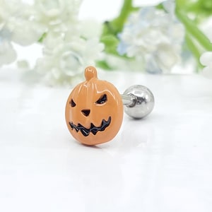 May include: Orange pumpkin-shaped Halloween themed body piercing with a black jack-o'-lantern face. The piercing is made of stainless steel and has a ball end.