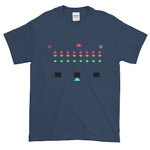 Könnte beinhalten: Ein marineblaues T-Shirt mit einem pixelartigen Bild eines klassischen Arcade-Spiels. Das Spiel zeigt ein Raumschiff, Außerirdische und einen Punktestand von 0.