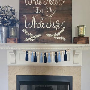Tassel garland with navy, Carolina blue, and white yarn tassels on wood beads, styled on a white fireplace mantel – North Carolina dorm decor, graduation party banner, handmade college room decoration