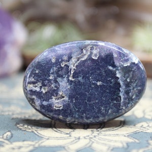 May include: A smooth, oval-shaped blue agate stone with white and gray markings. The stone is polished and has a glossy finish.