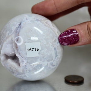 May include: White agate sphere with a natural druzy crystal formation and a label that reads "1671e".