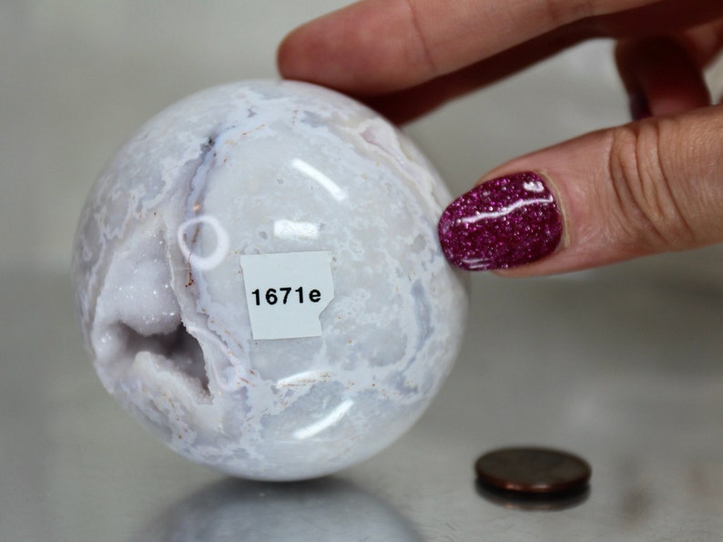 May include: White agate sphere with a natural druzy crystal formation and a label that reads "1671e".
