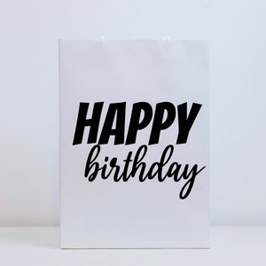 K&ouml;nnte beinhalten: Wei&szlig;e Geschenkt&uuml;te mit schwarzem Text, der "Happy Birthday" lautet.