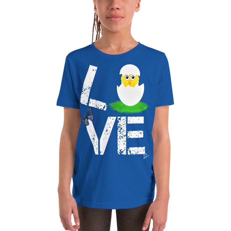 K&ouml;nnte beinhalten: Ein k&ouml;nigsblaues T-Shirt f&uuml;r Jugendliche mit einem wei&szlig;en, abgenutzten Aufdruck des Wortes "LOVE" mit einem K&uuml;ken, das aus einem Ei im "O" schl&uuml;pft.