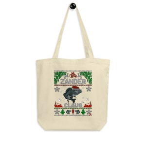 Può includere: Una borsa tote in tela beige con un design natalizio che presenta un pesce con un cappello di Babbo Natale e il testo "Zander Claus".