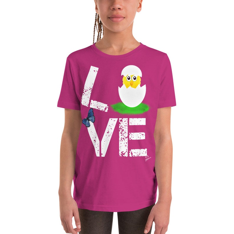 K&ouml;nnte beinhalten: Ein pinkfarbenes T-Shirt in Kindergr&ouml;&szlig;e mit einer wei&szlig;en, abgenutzten Grafik des Wortes "LOVE" mit einem K&uuml;ken, das aus einem Ei im "O" schl&uuml;pft.