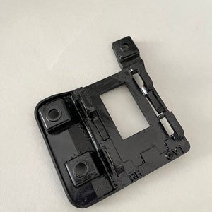 May include: Black plastic part with two holes and the letters "RH" and "CV1" printed on it.