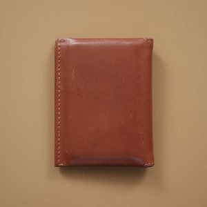 May include: A brown leather wallet with a stitched edge.