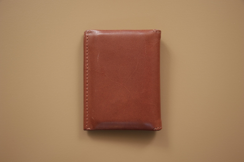 May include: A brown leather wallet with a stitched edge.