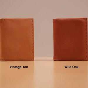 May include: Two leather wallets in different colors. The wallet on the left is a light brown color labeled "Vintage Tan". The wallet on the right is a reddish brown color labeled "Wild Oak".