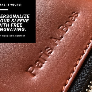 May include: Close-up of a brown leather sleeve with a zipper. The sleeve has the text "Paris A. Boes" embossed on it. The text "MAKE IT YOURS! PERSONALIZE YOUR SLEEVE WITH FREE ENGRAVING. FOR MORE INFO. CONTACT US" is visible in the background.