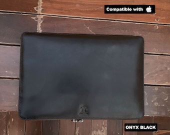 May include: Black leather laptop sleeve with a zipper closure. Compatible with Apple products. The sleeve has a small logo on the bottom.