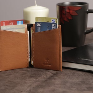 May include: A brown leather wallet with a flap closure and a brand name "ALDONA" embossed on the front. The wallet is open and has several credit cards inside.