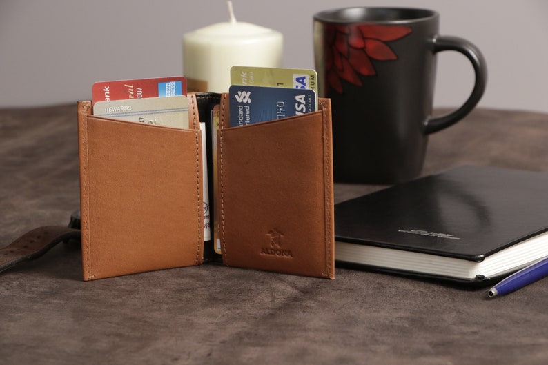 May include: A brown leather wallet with a flap closure and a brand name "ALDONA" embossed on the front. The wallet is open and has several credit cards inside.