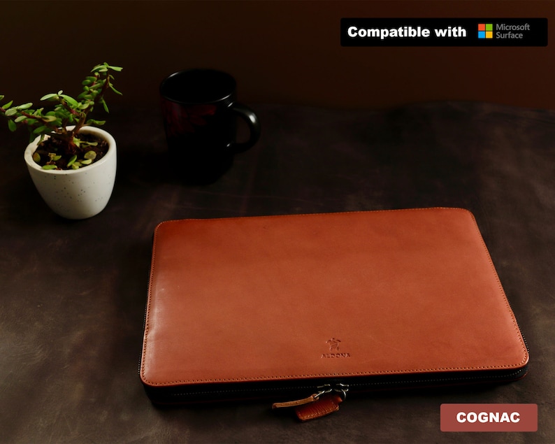 Puede incluir: Una funda para port&aacute;til de cuero marr&oacute;n co&ntilde;ac con cierre de cremallera. La funda tiene un logotipo en relieve sutil y es compatible con los dispositivos Microsoft Surface.