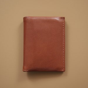 May include: A brown leather wallet with a stitched edge.