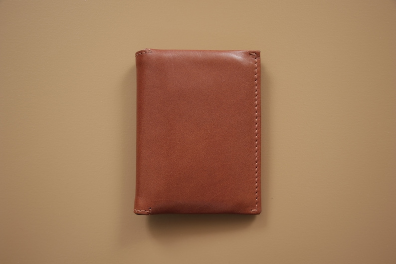 May include: A brown leather wallet with a stitched edge.