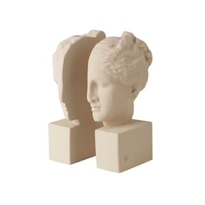 Può includere: Un paio di ferma libri in ceramica bianca a forma di profilo di testa di donna. I ferma libri sono uniti, con una testa rivolta a sinistra e l'altra a destra.