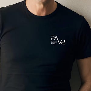K&ouml;nnte beinhalten: Schwarzes T-Shirt mit Rundhalsausschnitt und wei&szlig;em Logo-Text "PAVd" &uuml;ber "CLEMENT & INES". Das Shirt besteht aus einem glatten, dunklen Stoff. Das Logo ist ein modernes, minimalistisches Design.
