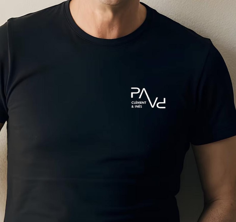 K&ouml;nnte beinhalten: Schwarzes T-Shirt mit Rundhalsausschnitt und wei&szlig;em Logo-Text "PAVd" &uuml;ber "CLEMENT & INES". Das Shirt besteht aus einem glatten, dunklen Stoff. Das Logo ist ein modernes, minimalistisches Design.