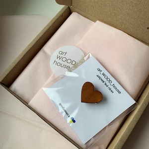 May include: A small wooden heart-shaped ornament in a clear plastic bag with a white card that says "art_WOOD_house Деревяні піні" and a sticker that says "art WOOD house".