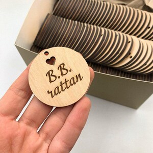 May include: A wooden tag with the text "B.B. rattan" and a small heart cutout. The tag is light brown and has a hole at the top for hanging.
