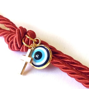 May include: Red braided rope keychain with a gold key ring, a gold cross charm, and a blue evil eye charm.