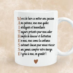 Peut inclure: Mug blanc en céramique avec une anse incurvée. Le mug présente du texte noir en français, dont le mot "MAITRESSE" en grandes lettres, et un petit cœur marron. Le mug est un cadeau pour un professeur.