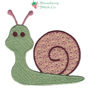 Puede incluir: Caracol verde bordado con antenas rosas y una concha rosa y beige con lunares blancos.