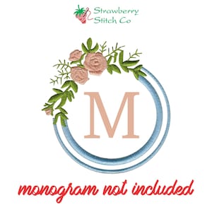 May include: A blue and white wreath with pink flowers and green leaves. The letter "M" is in the center of the wreath. The text "monogram not included" is below the wreath.