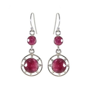 May include: A pair of silver dangle earrings with two pink gemstones. The larger gemstone is set in a circular frame.