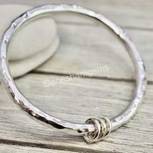 Peut inclure: Un bracelet jonc en argent martel&eacute; avec une fermeture nou&eacute;e. Le bracelet est en argent sterling et a une finition martel&eacute;e.