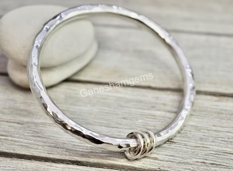 Peut inclure: Un bracelet jonc en argent martel&eacute; avec une fermeture nou&eacute;e. Le bracelet est en argent sterling et a une finition martel&eacute;e.