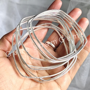 May include: A set of ten silver square-shaped bangles. The bangles are stacked on top of each other and are all the same size.