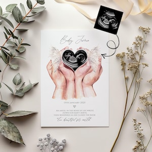 Puede incluir: Una ilustraci&oacute;n de acuarela de dos manos sosteniendo un coraz&oacute;n con una imagen de ultrasonido dentro. El coraz&oacute;n tiene alas de &aacute;ngel y el texto "Baby Jaskie" est&aacute; escrito en la parte superior. El texto debajo de la imagen dice "15th January 2025" y "Un &aacute;ngel en el libro de la vida escribi&oacute; el nacimiento de nuestro beb&eacute;. Luego susurr&oacute; al cerrar el libro "Demasiado hermoso para la tierra."