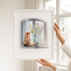 May include: A framed watercolour print showing a ginger tabby cat looking out of a window. A blue vase contains flowers. The print includes the name "Paley" and the quote "SOME SOULS WATCH THE WORLD WITH WONDER AND TEACH US TO DO THE SAME."