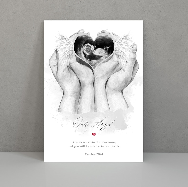 Puede incluir: Un dibujo en blanco y negro de dos manos sosteniendo una imagen de ultrasonido en forma de coraz&oacute;n con alas de &aacute;ngel. El texto "Our Angel" est&aacute; escrito en cursiva con un peque&ntilde;o coraz&oacute;n rojo debajo. El texto debajo dice "You never arrived in our arms, but you will forever be in our hearts. October 2024."