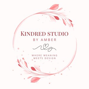 以下が含まれることがあります： Kindred Studio by Amberのロゴ。水彩画風のピンクの花柄アクセントをあしらった円形デザイン。スタジオ名、名前「Amber」、そして「Where Meaning Meets Design」というキャッチコピーが含まれています。
