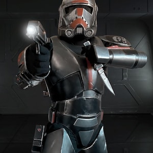 May include: A detailed image of a futuristic soldier in a dark, metallic suit with red accents. The soldier is holding a weapon with a bright light and a knife. The helmet has a distinctive design, and the overall aesthetic suggests a science fiction theme.